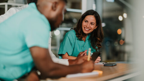 Healthcare professionals on night shift collaborating on medical records, smiling.
