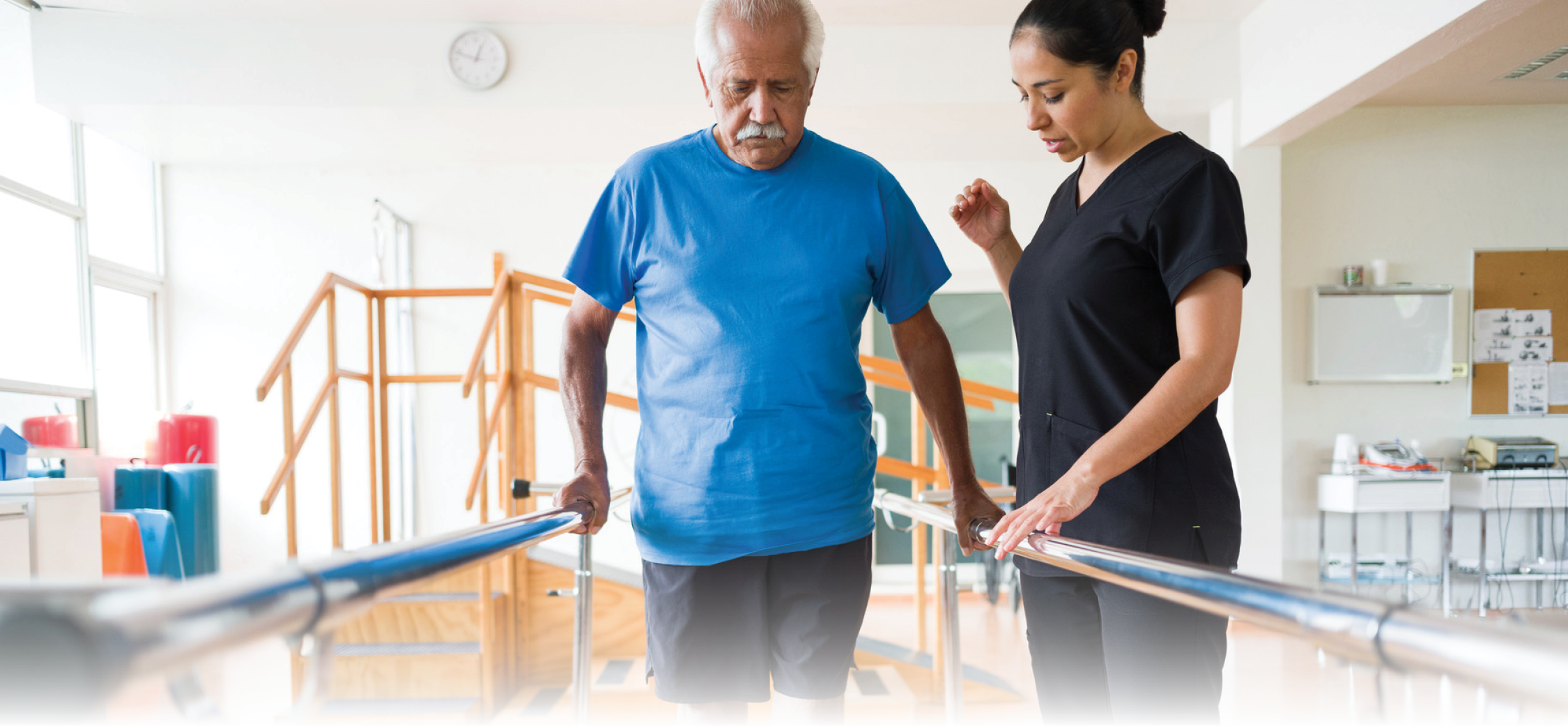 Therapist assisting senior man on parallel bars