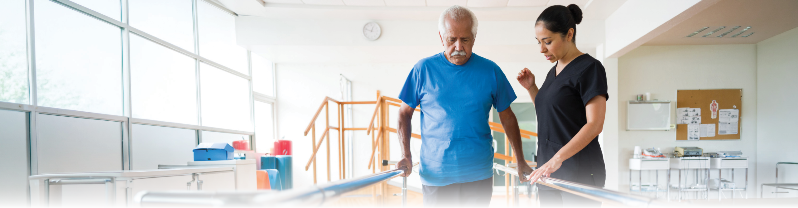 Therapist assisting senior man on parallel bars
