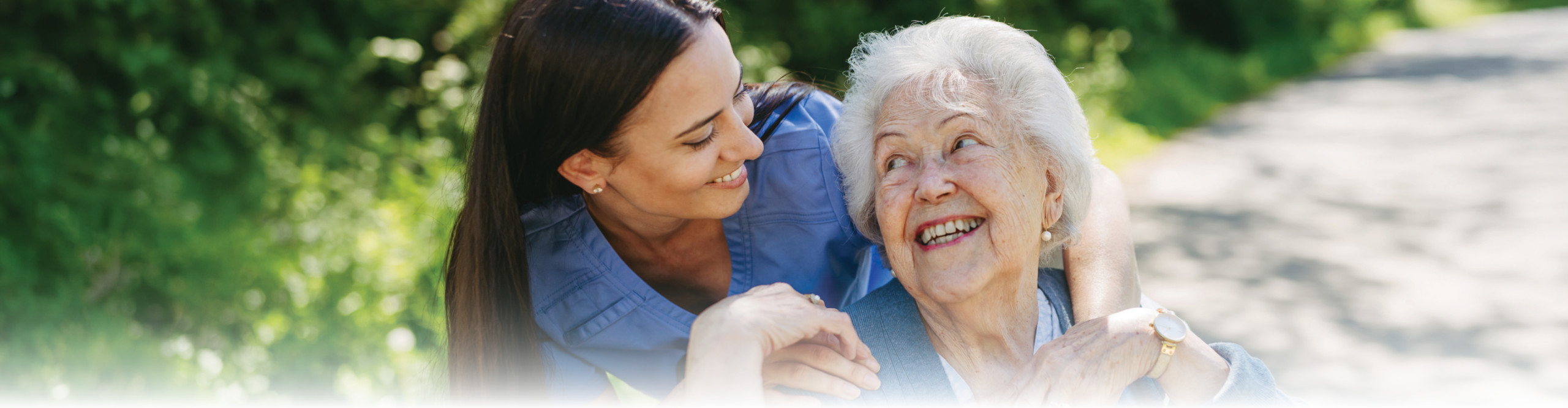 Caregiver pushing senior woman in wheelchair.