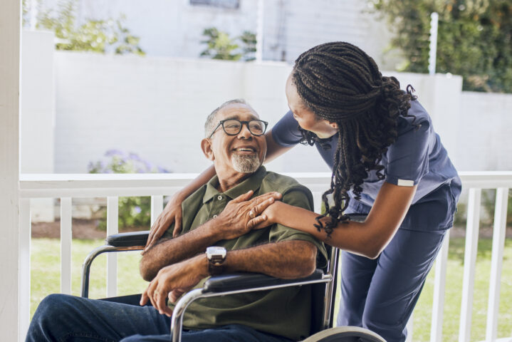 Young female nurse hugging an elderly man in a wheelchair
